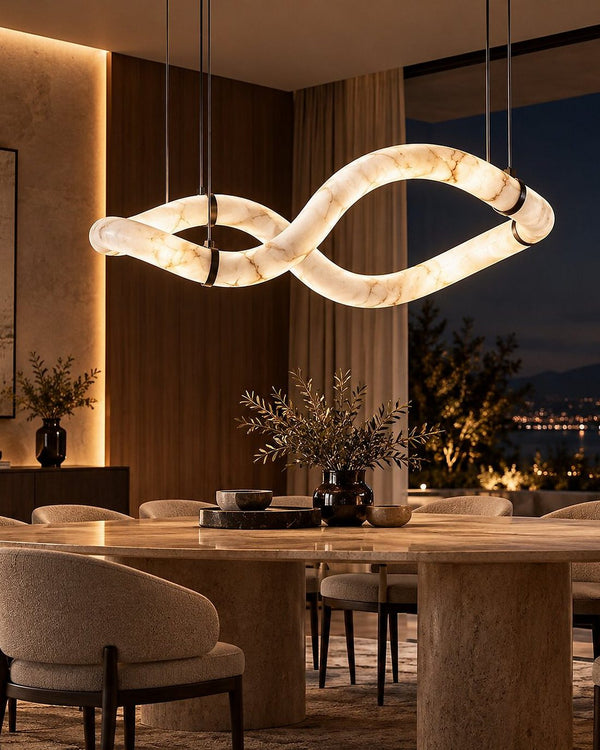 The Halo Infinia chandelier, a twisting alabaster ring, over a dining table at night