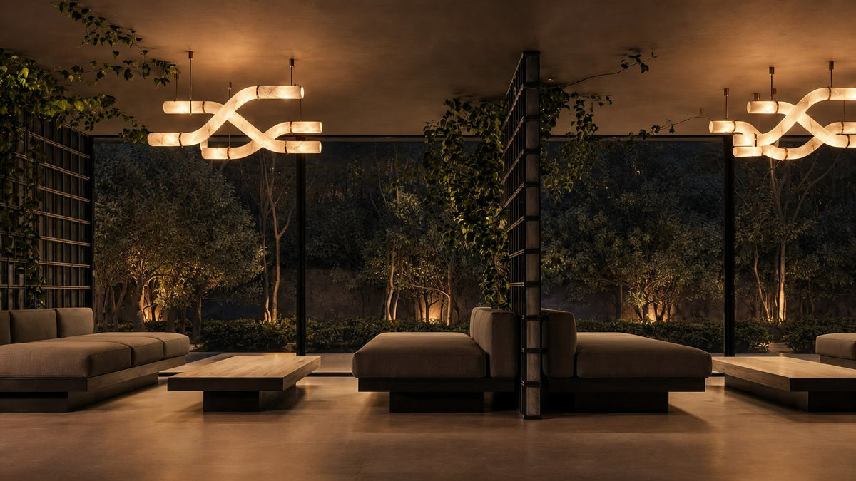 Two woven alabaster chandeliers glowing in a garden-glass living room at night